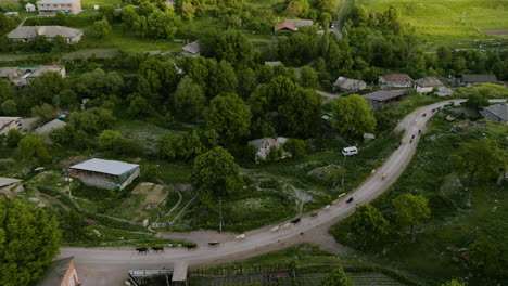 Vista-Aérea-De-Vacas-En-El-Camino-Dirigido-Por-Pastor-A-Través-Del-Pueblo-De-Montaña-En-Georgia