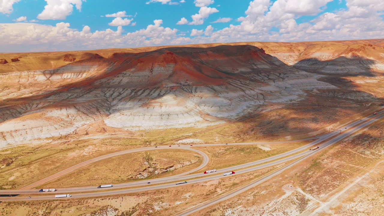 Busy roads with loops at the foot of picturesque mountains. Beautiful rocks in shadows of the clouds. Cloudy blue sky at backdrop.