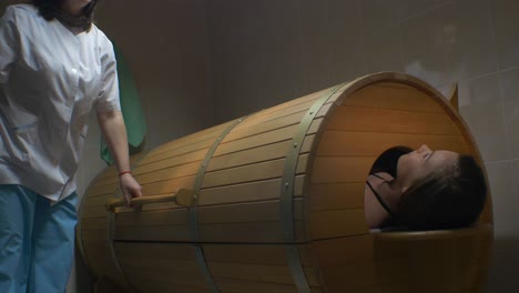 woman in a wooden barrel sauna therapy