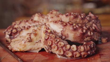 muñeca de primer plano extremo dentro y fuera de pulpo caliente medio cocido al vapor en una tabla de cortar de madera, preparación de platos de mariscos, toma de concepto de cocina