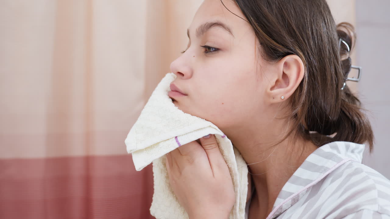 Gentle Towel Pat For Cleansing, Female Figure Applies Soft Cloth To Her Face Following Cleaning Routine, Caucasian Woman Gently Presses Towel Against Her Face In Cozy Bathroom Setting