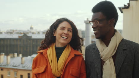 multiethnic man and woman walking on rooftop terrace and speaking