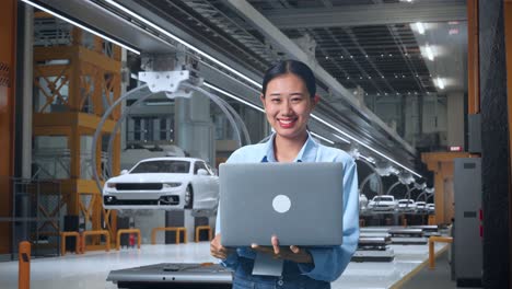 mujer trabajando en una computadora portátil en una fábrica automotriz moderna