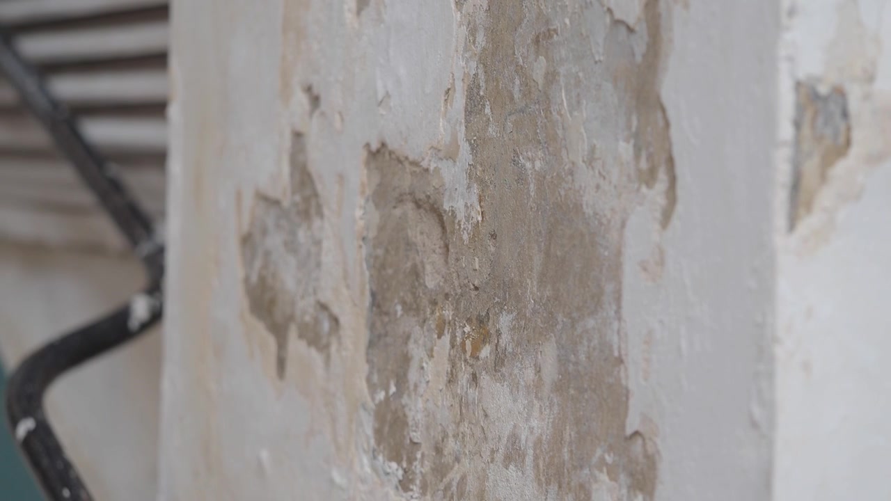 Primo piano di muro bianco danneggiato con vernice scrostata.