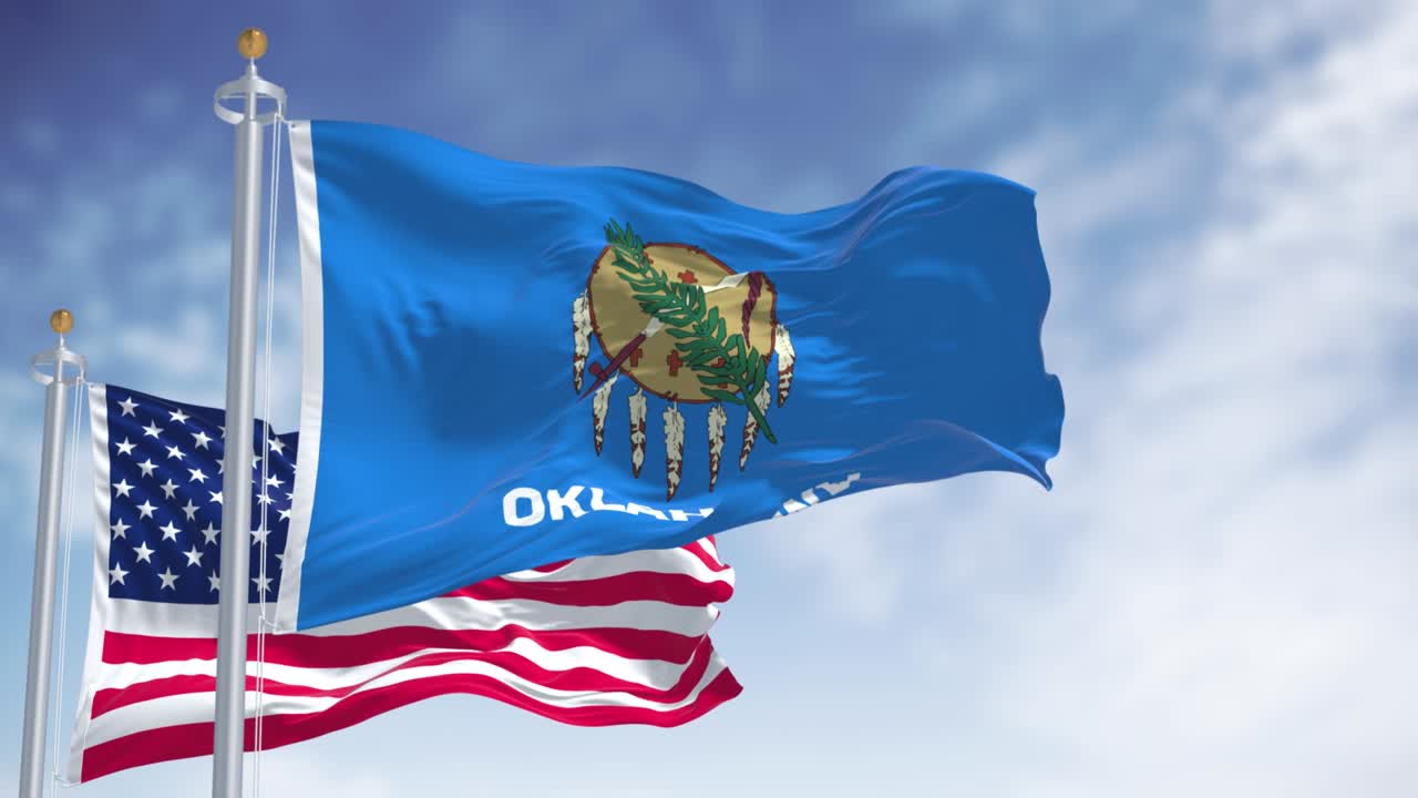 la bandera del estado de oklahoma ondeando junto con la bandera nacional de los estados unidos de américa