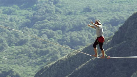 highline walking over a valley with trees below in slow-motion