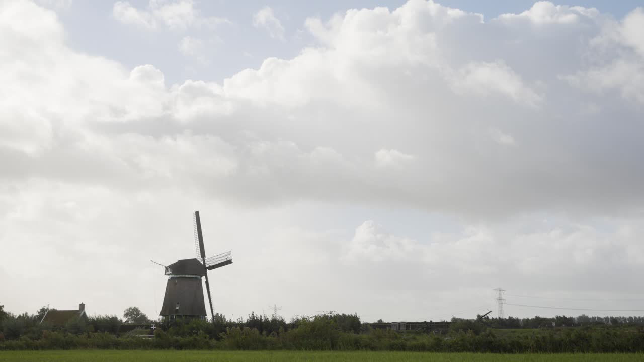 Wide shot of a classic Dutch windmill standing in the green countryside of the Netherlands