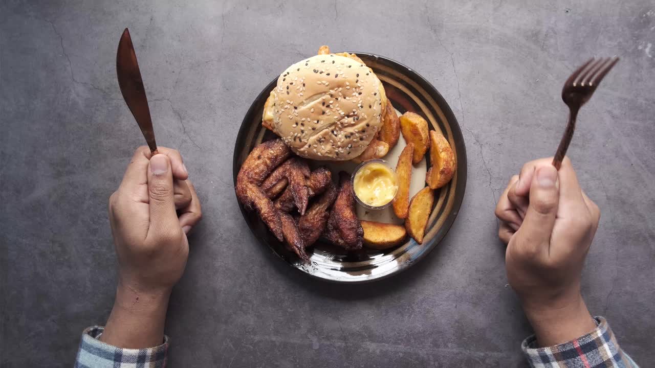 тарелка еды с бургером, картошкой фри и куриными крыльями