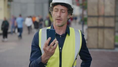 portrait mature construction engineer man using smartphone browsing working on site wearing safety helmet reflective clothing in city slow motion