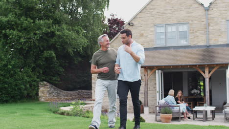 senior father with adult son walking and talking in garden together