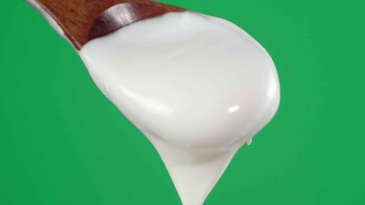 с деревянной ложкой падает кислый крем.