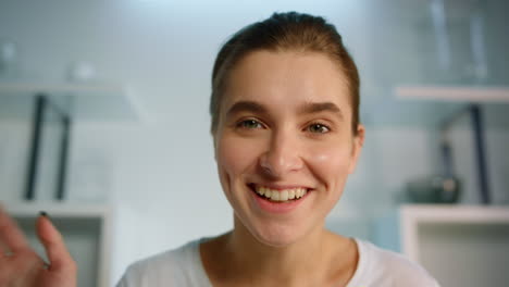 Smiling-girl-recording-blog-at-home-closeup.-Beautiful-blond-woman-waving-hand