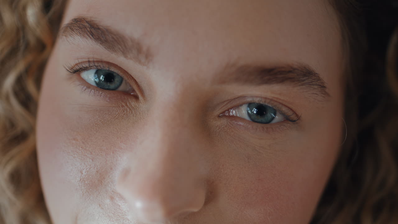 Woman open blue eyes looking camera macro closeup. Serene girl with focused gaze