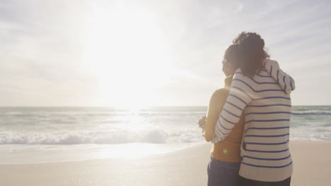 back view of happy hispanic couple standing and embracing on beach