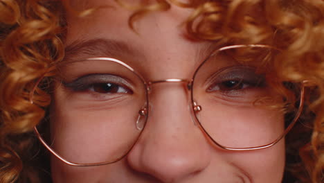 close-up portrait of a woman with curly hair, wearing glasses and smiling