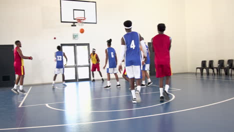 multiracial male basketball players playing basketball, bouncing and throwing basketball in gym