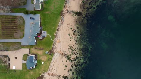 an aerial, top down view of the waterfront properties and beach of the long island sound in greenport, ny on a sunny day