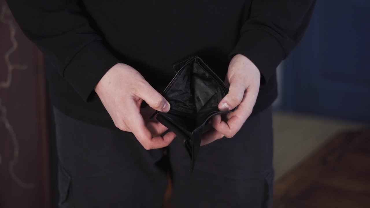 Man holding an empty wallet, showing financial hardship, bankruptcy, debt, and money shortage concept