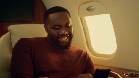 cheerful man texting friend at plane window closeup. happy businessman enjoying