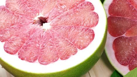 vista superior girar la fruta de pomelo roja con hojas en la mesa de madera en el jardín, la fruta del pomelo rojo con hojas con fondo de madera resolución 4k.