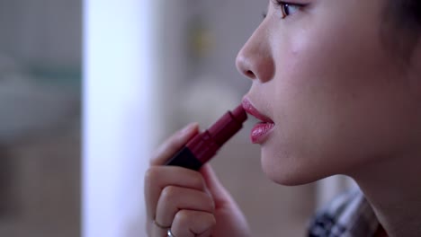 charming woman applying bright lipstick