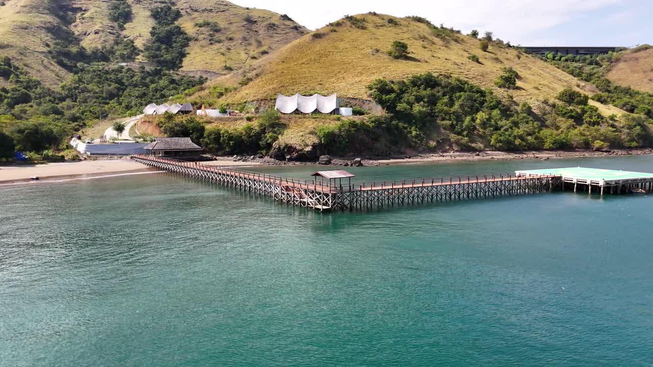 Drone che vola in cerchio attorno a un molo nell'oceano con due persone che camminano verso una piattaforma per elicotteri in 4K