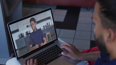hombre afroamericano haciendo una videollamada con una colega de oficina en una computadora portátil en casa