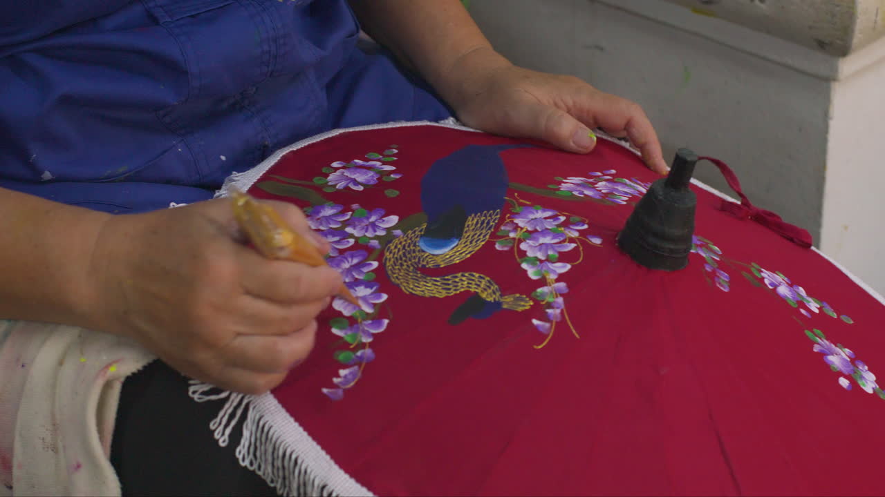Artisan Painting Colorful Peacock And Flowers On Red Paper Umbrella At Workshop. Bo Sang Village In Chiang Mai, Thailand. closeup shot