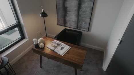 minimal desk setup in a home office with a wooden desk, lamp, and leather chair