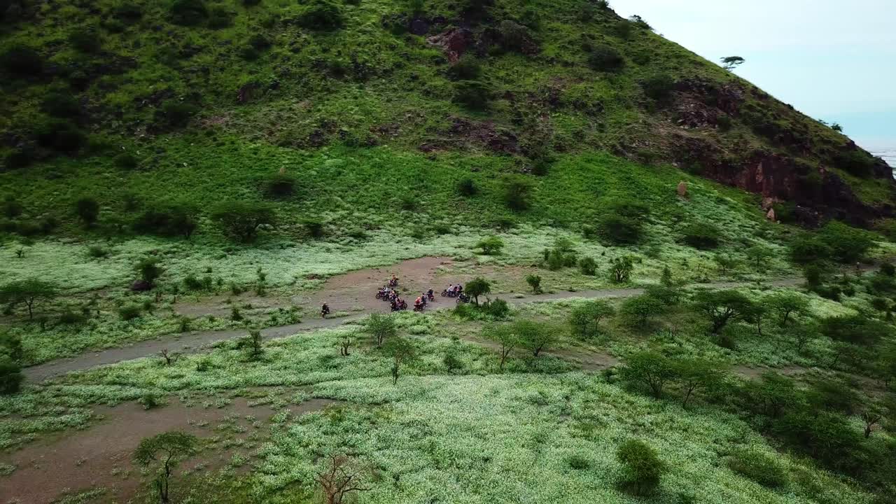 мотоциклисты у озера натрон в танзании во время сафари-тура - съемка с беспилотника