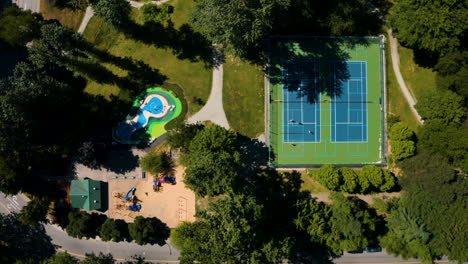 Top-down-aerial-view-over-tennis-courts-and-a-playground-in-Burnaby,-Greater-Vancouver