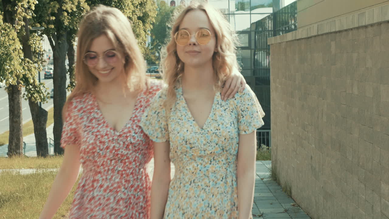 dos mujeres jóvenes caminando por una ciudad, sonriendo y riendo.