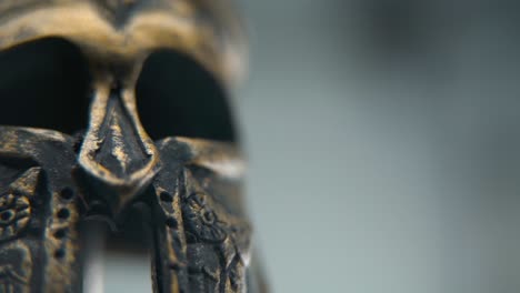 a close-up macro shot of a spartan design, two different ancient warrior metal bronze helmets, textured shapes, studio lighting, full hd cinematic video, hyper slow motion 120 fps, pan left