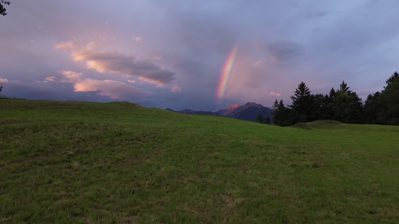 Drone rise above Fields in the Mountains with Rainbow in Background during Sunrise