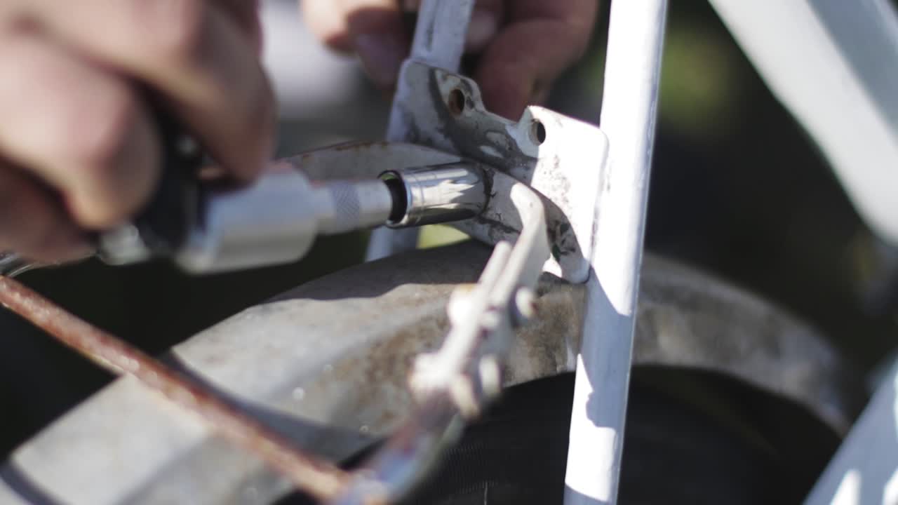 Unscrewing a screw on an old rusty bicycle with a ratchet. Bike repair.