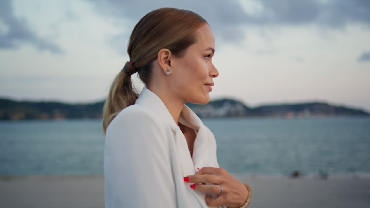 Pretty lady going embankment at cloudy evening close up. Woman walking coast