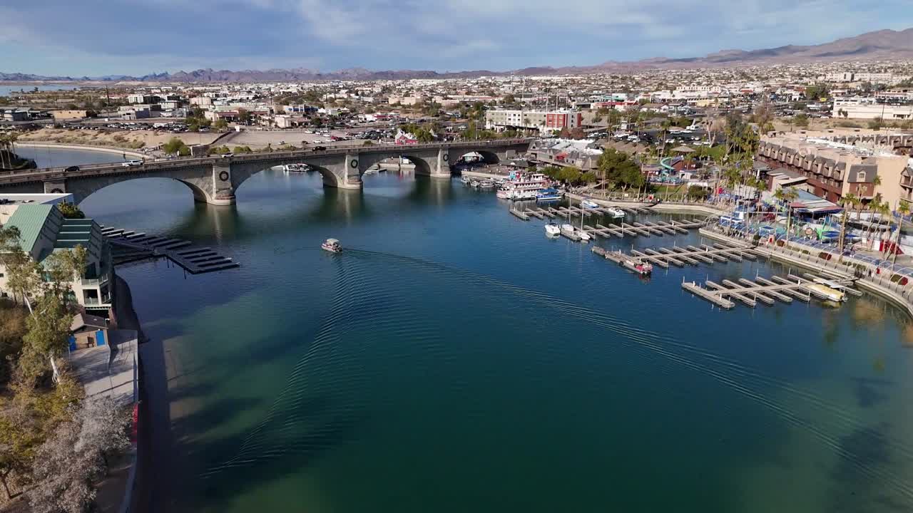 Drone Flying over water canal towards bridge. Surrounded by boats, hotels and trees. Mid afternoon at London Bridge in Lake Havasu City Arizona