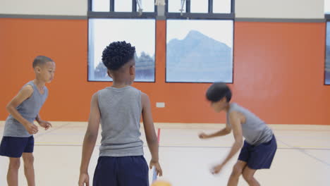 in school gym, three boys playing basketball and practicing together