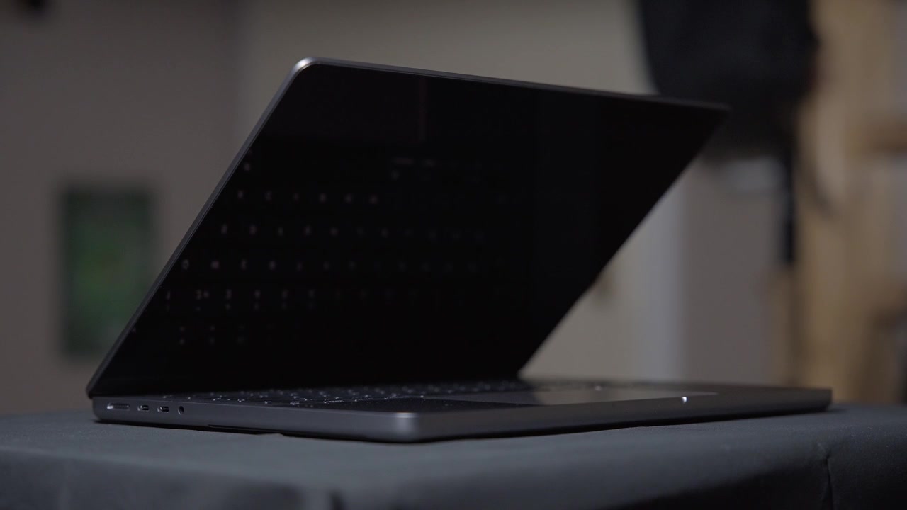 Filmato cinematografico di un Apple M1 MacBook Pro da 14 pollici mostrato con una luce in movimento, ripreso con una lunghezza focale stretta in 4K al rallentatore in studio con luce controllata.
