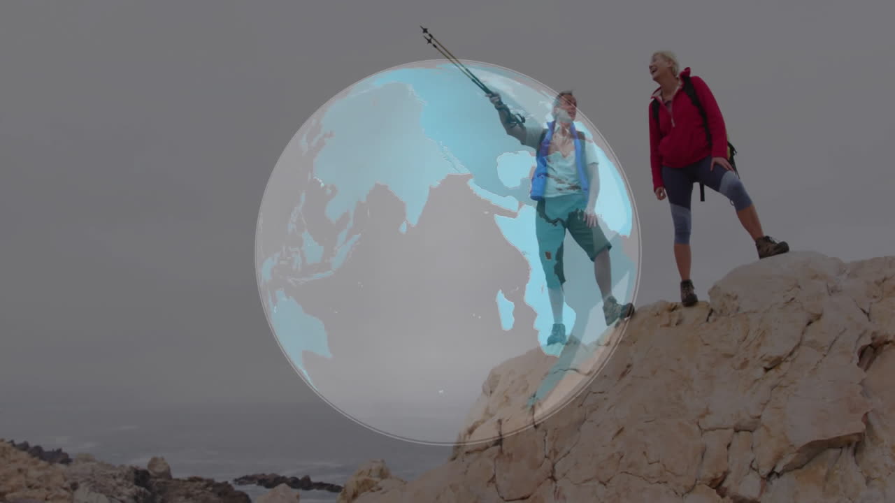 Couple hiking on coast with backpacks, trekking poles, showing digital globe overlay for technology