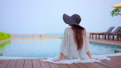 sitting with her back to the camera a woman looks around the resort and ocean view