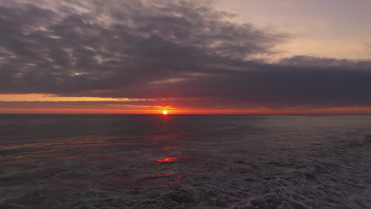 carro aéreo bajo sobre las olas rompiendo en la playa durante la puesta de sol en iquique, chile