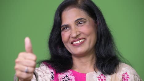 close up shot of mature happy beautiful indian woman smiling while giving thumbs up