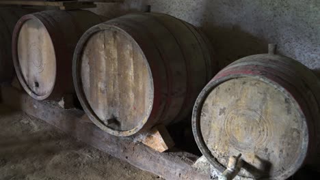 Aged wooden wine barrels in a dark rustic cellar