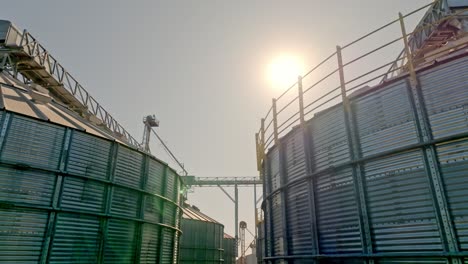 aerial dolly up shot revealing facility with metal grain silos storage for agricultural harvest