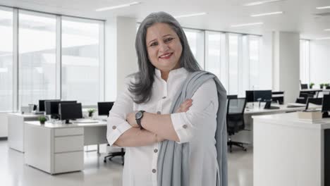retrato de una feliz mujer de negocios india de pie con las manos cruzadas