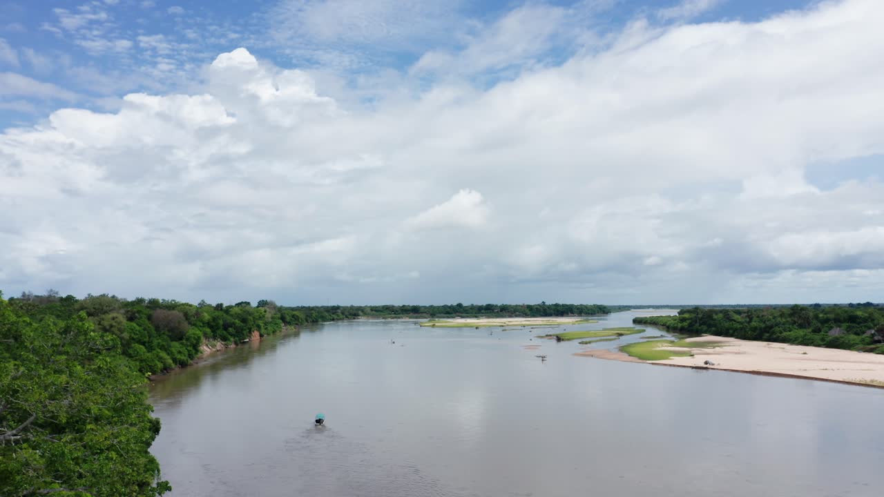 Aerial drone shot flying forward over a river in Selous, Tanzania, following a boat. Cloudy sky