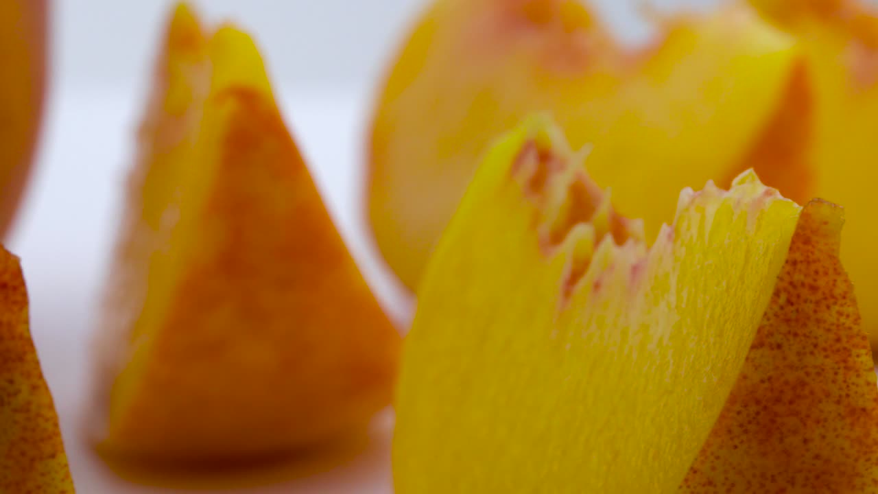Super close macro of a peach fruit slices. Rotating on the turntable. Isolated on the white background.