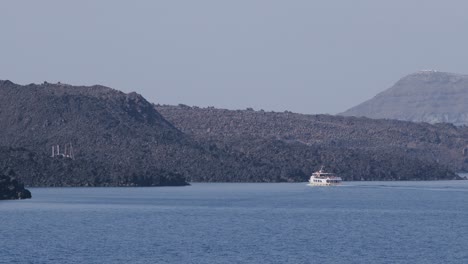boat sailing near volcanic rocks and hot springs in fira, santorini, greece