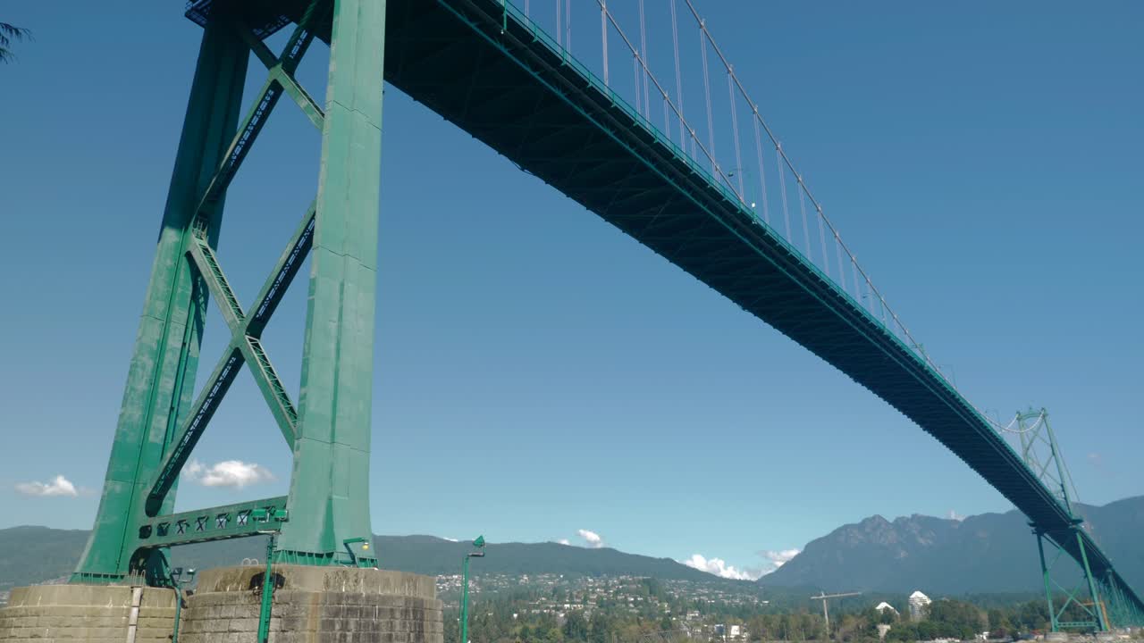 Cyclists ride along Vancouver's Stanley Park Seawall, under Lions Gate Bridge